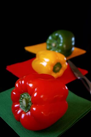 Tri-color bell peppers: red, yellow, green on black background. Focus selectiveの写真素材