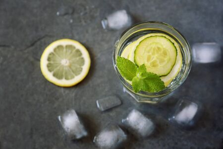 Cool refreshing drink: pure water, ice, lemon, cucumber and mint garnish. Top viewの写真素材