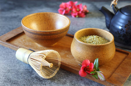 Matcha green tea in ceramic bowl and flowering japanese quince. toned image