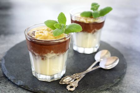 Two glass of homemade pudding with vanilla custard, banana and cocoaの写真素材