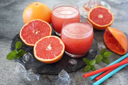Grapefruit pulp juice in two glasses and grapefruit halvesの写真素材