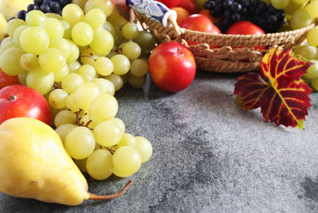 Background: autumn fruits in wicker basket. Grapes, red plums and pearsの写真素材