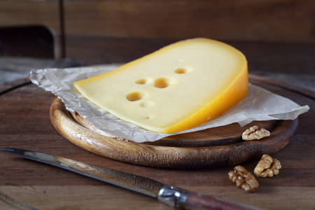Maasdam cheese and walnuts on a wooden cutting board
