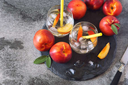 Summer diet cold drink: detox pure water with nectarine and ice, two glasses on dark background. Top viewの写真素材