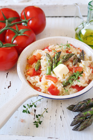 Tomato risotto with green asparagus, bunch of tomatoes and olive oilの写真素材