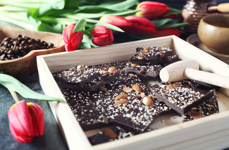 Holiday mood. Dark  handmade chocolate with nuts, coffee and red tulipsの写真素材