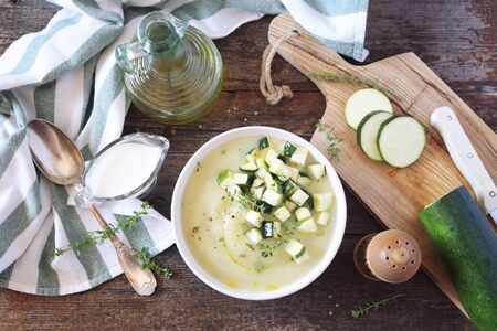 Zucchini vegetable cream soup, thyme and olive oil dressing on wooden background. Rustic style, top viewの写真素材