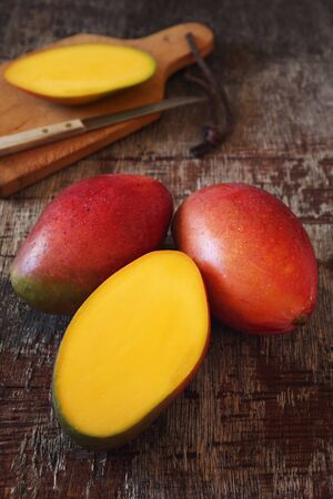 Tropical mango fruit, intact and half on wooden background. Selective focusの写真素材