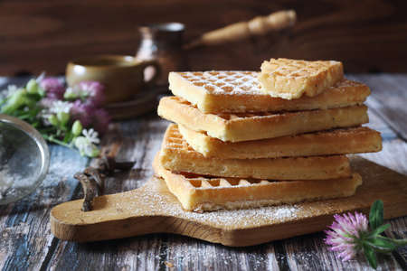 Traditional belgian waffles, powdered sugar dressing and coffee cup for sweet breakfast, rustic styleの写真素材