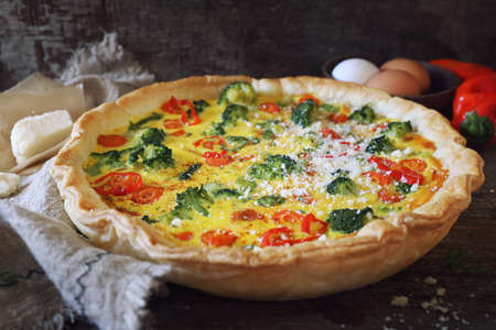 French cuisine. Quiche pie with broccoli, carrots, hot peppers and parmesan cheese, on wooden...