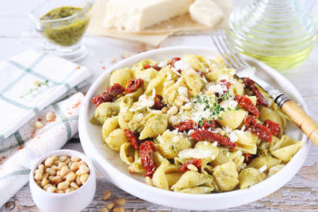 Conchiglie rigate pasta with pesto sauce and sun dried tomatoes, grated parmesan cheese and pine nut, thyme and olive oil dressingの写真素材