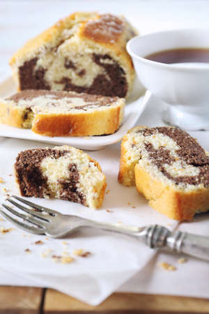 Homemade traditional marble cake and cup of black tea on light background
