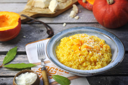 Italian food. Plate of pumpkin risotto and grated parmesan cheese on wooden backgroundの写真素材