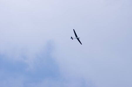 Glider in flight with cloudy sky