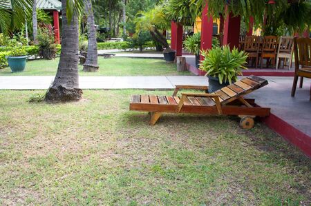 Empty wooden deck chair in beautiful garden