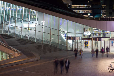 Arnhem, Netherlands - December 18, 2019: Entrance of station Arnhem at night, people blurred by...