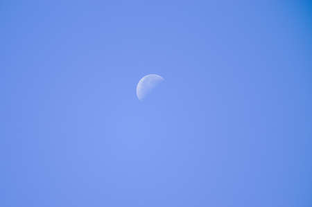 Moon in daytime on a clear blue skyの写真素材