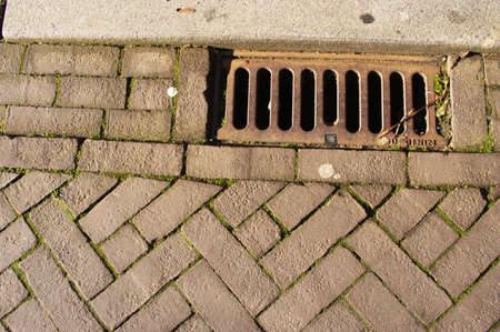 Closeup of a rain drainage grid in the streetの写真素材