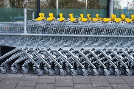 A row of silver and yellow shopping carts at a supermarket