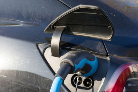 Closeup of a blue and black power plug of a electric car with the charger cable attached