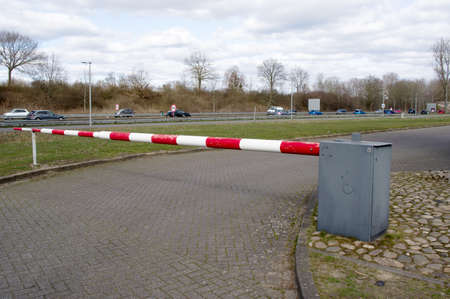 Closeup of a closed barrier gate with traffic in the background