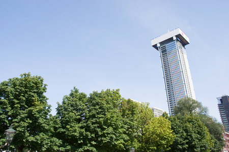 Skyline with a skyscraper of Rotterdam with trees in the foreground in the Netherlandsのeditorial素材