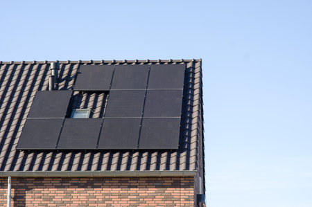 Brown roof with solar panels of a house with a clear blue skyの写真素材