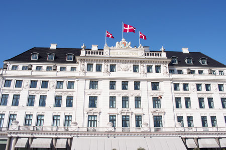 Copenhagen, Denmark - April 6, 2023: White facade of Hotel d'Angleterre with danish flags on top in the center of Copenhegen with a clear blue skyのeditorial素材