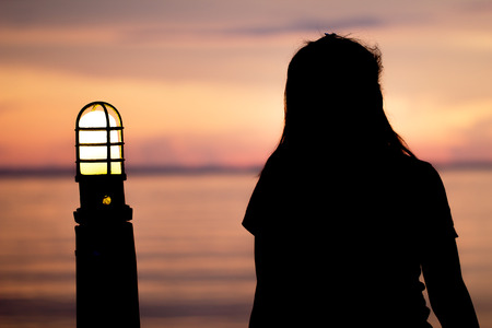 Lonely woman sitting alone looking the ocean moments sunset.are Lovely. Style abstract shadows.silhouette.の写真素材