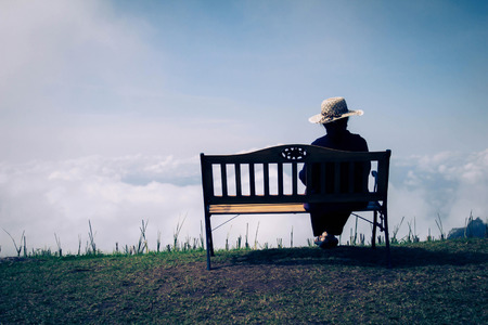 Emotional sitting lonely sad shadows woman concerned on a wooden chair. In the background is a natural idea.の写真素材