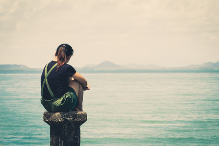 The girl sitting alone lonely at the sea. With lonelinessの写真素材