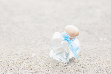 Heart shaped glass bottle on the sand. Decoration weddingの写真素材