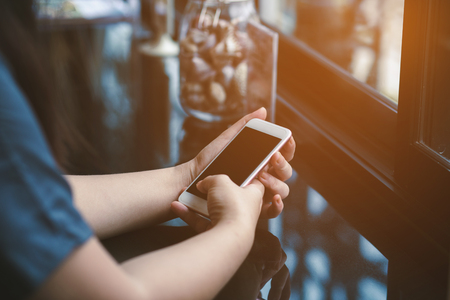 hand woman using smartphone in coffee shop and soft lightの写真素材