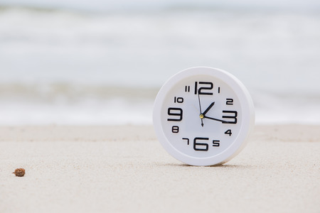 White alarm clock on natural beach. Holiday ideasの写真素材