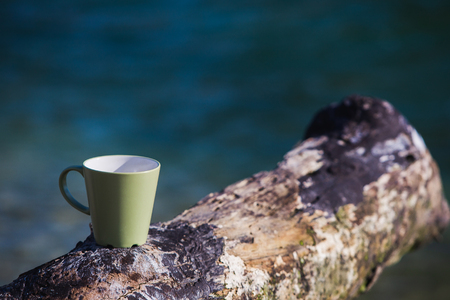 Coffee cup place on a piece of wood on the background seaの写真素材