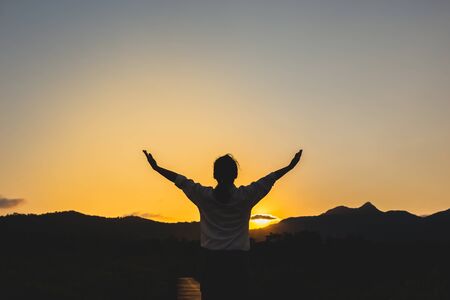 The girl stood praying to God on the sunset backgroundの写真素材