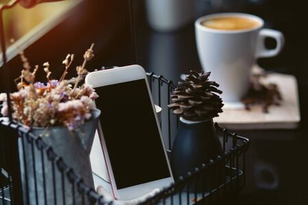 A smartphone with a cup of coffee on a table, a beautiful vintage style table.の写真素材