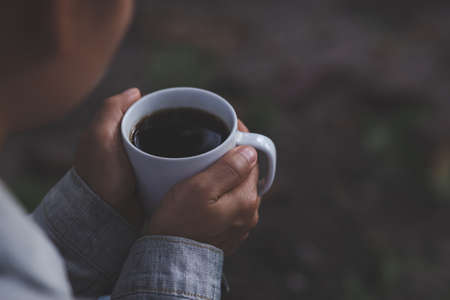 Relaxing view with hot coffee in hand In the forest during the rainy season Dark tone style Photos...