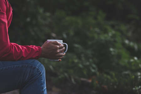 Relaxing view with hot coffee in hand In the forest during the rainy season Dark tone style Photos...