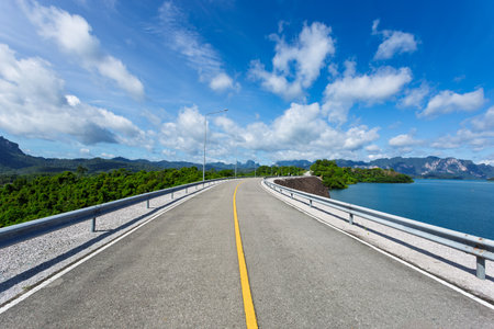 Asphalt road on the dam with blue sky and cloud background.の写真素材