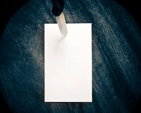 A piece of paper pinned by kitchen knife on a mist wooden backgroundの写真素材