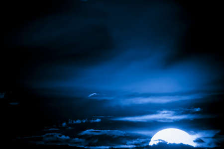 Fantastic glowing moon bathing in blue cloudsの写真素材