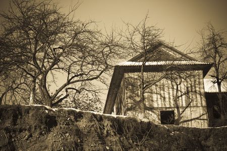 Sepia toned old-fashioned vintage village house with treesの写真素材
