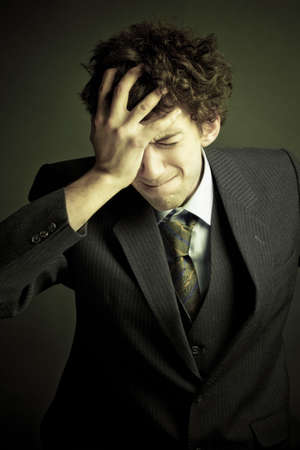 Young sad businessman with hands on his head.Emotional business trouble concept.