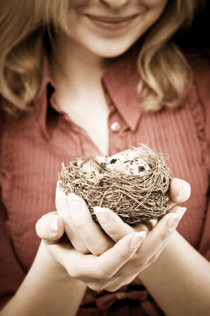 Young woman holding a bird nest in her hands. Conceptual enviromental cheerful image.の写真素材