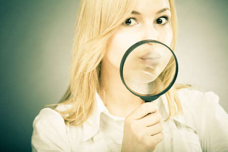  Excited girl with a loupe in her hand looking to camera. Fun business concept image with colored effectの写真素材