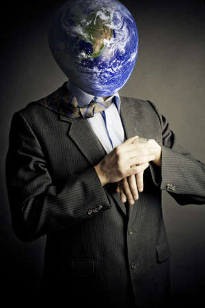 Businessman with planet instead of head looking to his watch. Conceptual creativity image.Earth in this montage provided by NASA (http://visibleearth.nasa.gov/)の写真素材