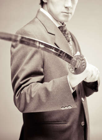 Old-fashioned businessman with sword in his arms. Traditions in business concept, business is a struggle concept, best defence is attack concept の写真素材