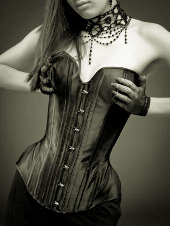 Sepia colors woman in leather corset decorated with necklace and earrings against vignette backgroundの写真素材