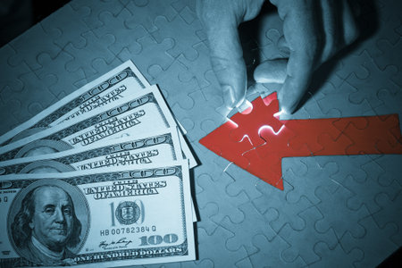 Male hand placing the last piece of puzzle to the red arrow pointed to money. Business concept image, blu tonedの写真素材
